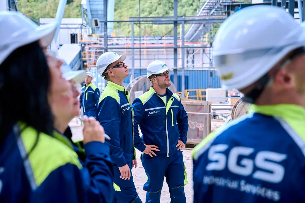 MitarbeiterInnen von SGS Industrial Services in individuell gestalteter Berufsbekleidung mit eigenem Design, Unternehmensfarben und Logo.